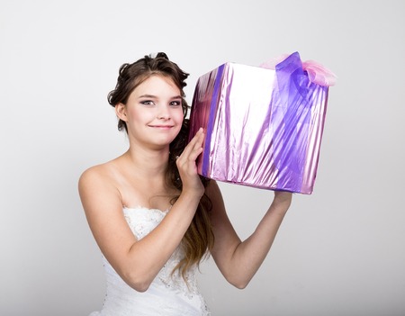 little girl in a white dress holding a box with a gift.の写真素材