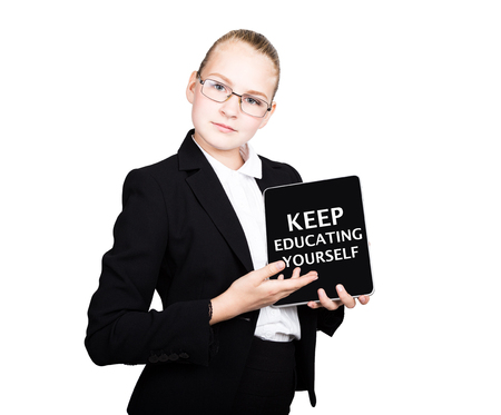 school girl in a business suit holds a pc tablet in his hands and looking into the camera, on a pc tablet inscription keep educating yourself.の写真素材