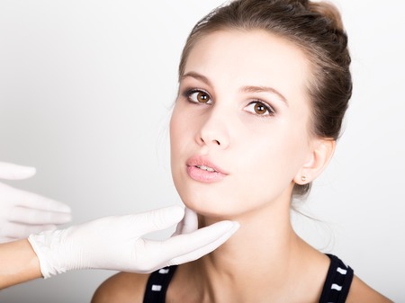 beautician hand's examining beautiful young female's faceの写真素材