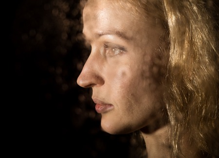 Smooth portrait of sexy model, posing behind transparent glass covered by water drops. young...