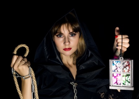 mysterious young woman holding rope and old flashlight. on a dark background.の写真素材