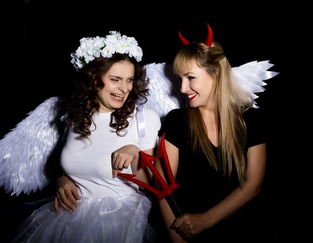 Portrait of angel and devil womans on a dark background.の写真素材
