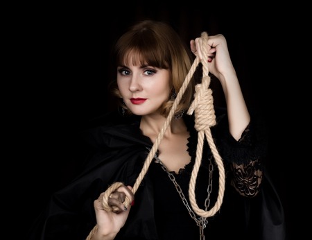mysterious young woman holding loop of the rope. on a dark background.の写真素材