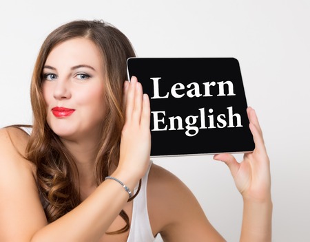 learn english written on virtual screen. technology, internet and networking concept. beautiful woman with bare shoulders holding pc tablet.の写真素材