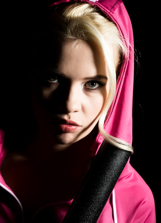 Playful young blonde in a tracksuit holding a baseball bat.の写真素材