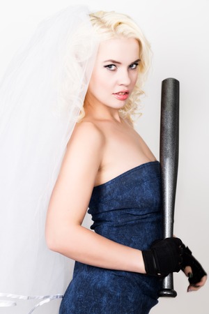 Beautiful blond bride wearing blue dress and weil with professional make-up holding baseboll bat.の写真素材