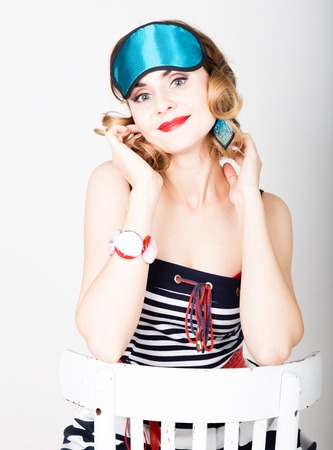 beautiful young woman in a striped dress and points for sleep, sitting on a chair and posing. sleeping eye covering mask.の写真素材