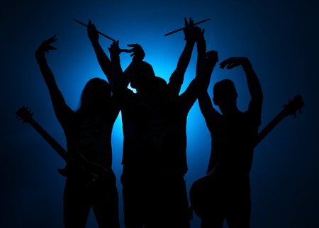 Band of young male musicians standing with instruments on a blue background.の写真素材