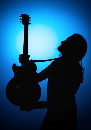 silhouette guitarists of a rock band with a guitar on a blue background.の写真素材
