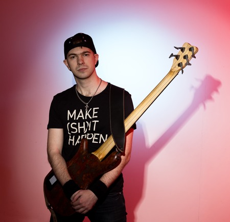 guitarists of a rock band with guitar on red background.