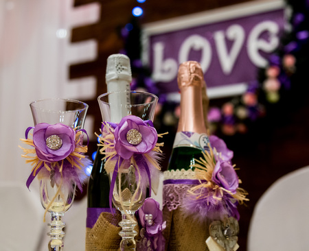 Love inscription on a wooden background, flashing lights and flowers. Bottle of champagne and glasses.の写真素材