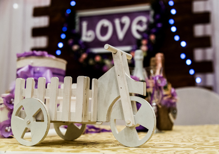 Love inscription on a wooden background, flashing lights and flowers. Close-up toy bike.の写真素材