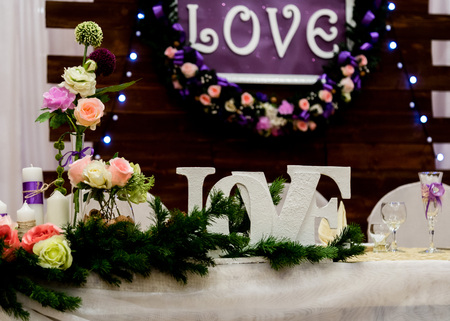 Love inscription on a wooden background, flashing lights and flowers. Candles and branch of pine.の写真素材