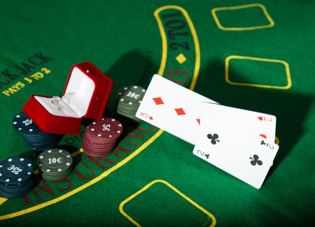 casino chips and a precious ring on a green poker table background, man throws cards with losing combinationの写真素材