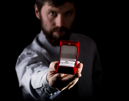 bearded man in a business suit gives a ring in the red box and expresses different emotions on a...