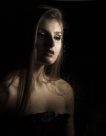 Portrait of a sensual young sexy woman wearing corset, touching her hair on black backgroundの写真素材