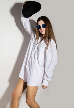 naked girl in a mans white shirt, sunglasses and black hatの写真素材