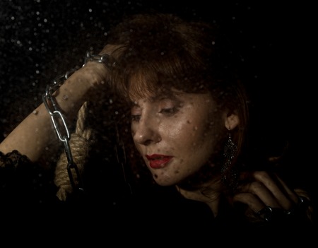 mysterious young woman holding rope. on a dark background