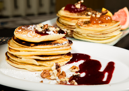 Homemade sweet pancakes with fruit jam on a white plate. Breakfast with stack topped blueberry jam and walnuts.の写真素材