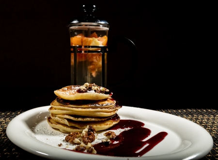 Breakfast with sweet pancakes topped blueberry jam, teapot with fruit teaの写真素材