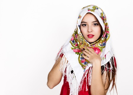 beautiful young woman dressed in a red dress and colored scarf posing in studioの写真素材