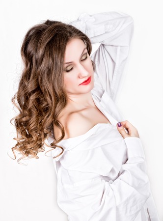 young beautiful brunette woman, attractive girl sitting in mans white shirt over his naked bodyの写真素材
