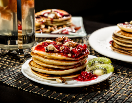Breakfast with sweet pancakes topped blueberry jam, teapot with fruit teaの写真素材