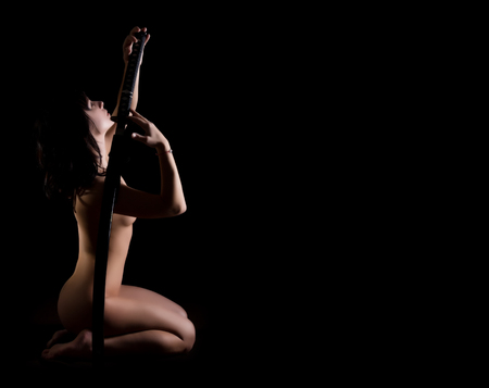 sexy nude woman with sword on dark background, free space for textの写真素材