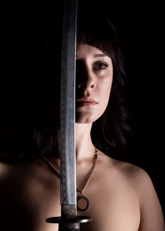 close-up sexy nude woman with sword on dark backgroundの写真素材