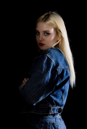 Fashion studio photo of young woman in danim jacket on dark backgroundの写真素材