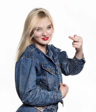 Sporty girl in denim jaket and jeans show middle finger, fuck you off sign on white background. indecent lifestyle conceptの写真素材