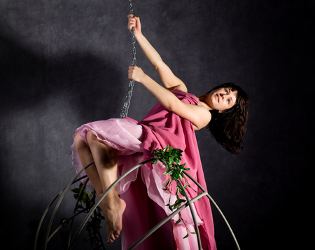 sexy elegance girl in a pink skirt, swinging on a metal swing. holding on to chainsの写真素材