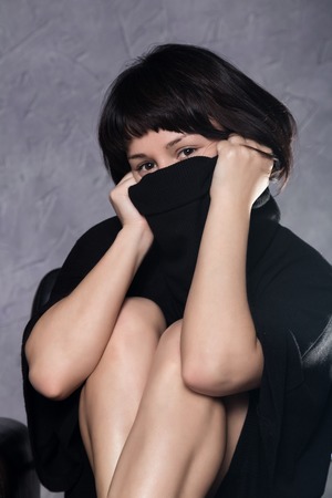 beautiful fashionable lady wearing a gothic black dress with high collar, poses in white smoke on a grey background.の写真素材