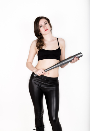 young pretty woman in leather pants and black top holds grey baseball batの写真素材
