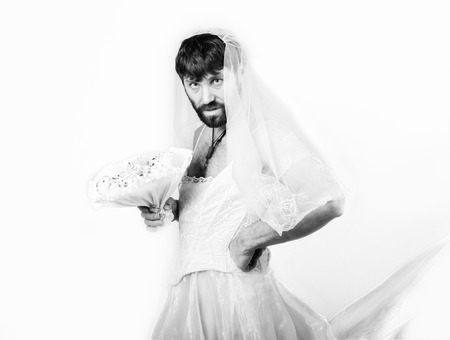 bearded man in a womans wedding dress on her naked body, holding a flower. on his head a wreath of flowers. funny bearded bride, black and whiteの写真素材