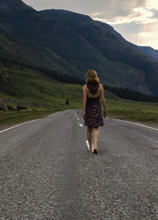 single barefoot woman is walking along the mountain road. Travel, tourism and people conceptの写真素材