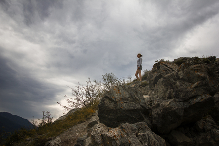 Beautiful woman standing on mountain top and contemplating the sky cloudsの写真素材