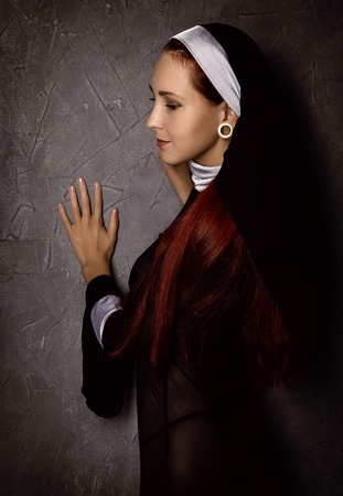 Beautiful sexy catholic nun posing on a dark background. religious conceptの写真素材