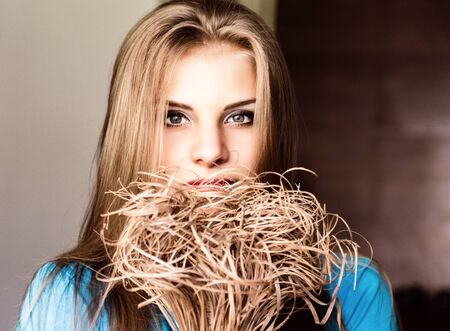 close up young blonde beauty woman with flowers on a dark background. professional makeupの写真素材