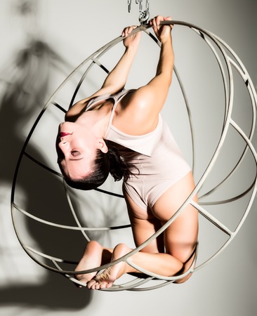 sexy woman in a beige swimsuit on a metal cage on a white backgroundの写真素材