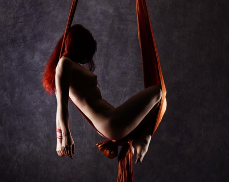 Beautiful nude dancer on aerial silk, graceful contortion, acrobat performs a trick on a ribbons.の写真素材