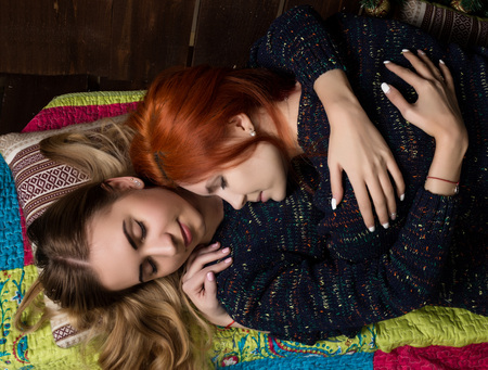 two pretty lesbian girlfriends kissing and hugging in a cozy atmosphere