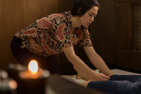 beautiful girl doing thai back massage in spa saloon. Thai massage or Thai yoga massage treatmentの写真素材