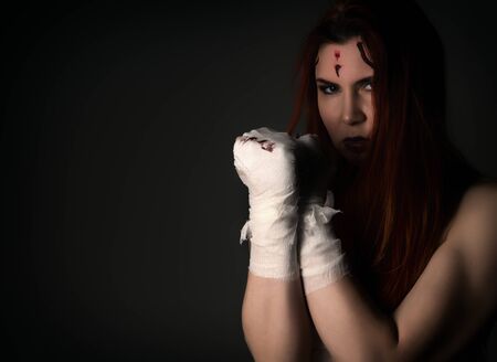 Beautiful young female fighter after the fight on a dark background. girls in martial arts. free space for your textの写真素材