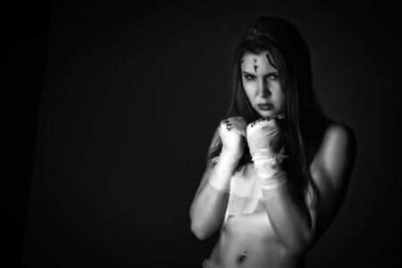 Beautiful young female fighter after the fight on a dark background. girls in martial arts. black and white. free space for your textの写真素材