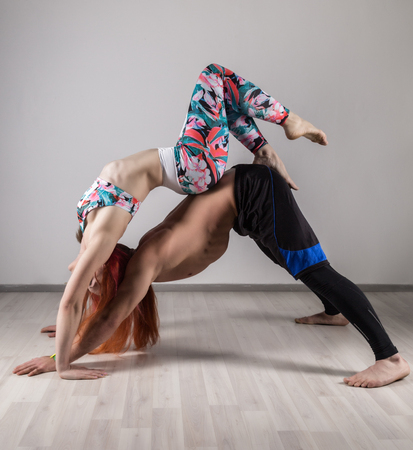 sports man and woman doing acroyoga exercises in a gray backgroundの写真素材