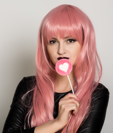 Beautiful young girl with pink hair, smile and brigth light with candy lolipopの写真素材