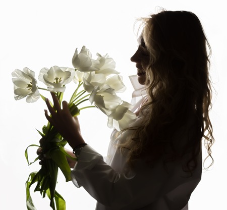 silhouette of beautiful curly girl with spring flowers tulips on a white backgroundの写真素材