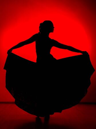 silhouette of spanish girl flamenco dancer on a red backgroundの写真素材