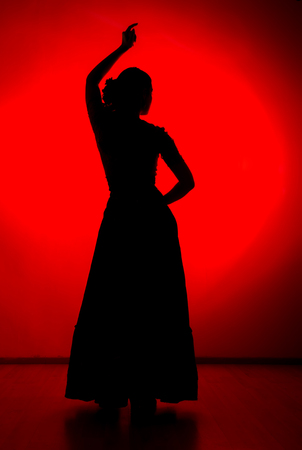 silhouette of spanish girl flamenco dancer on a red backgroundの写真素材
